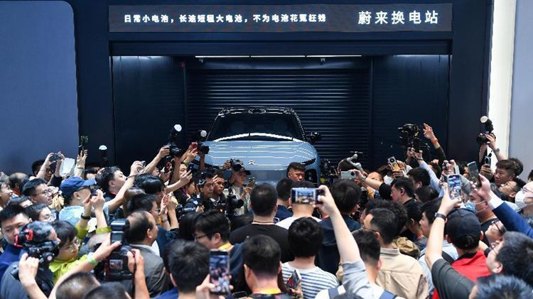 4月25日，在2024北京國際車展上，一群參觀者在蔚來汽車展台參觀電動汽車換電站演示。新華社記者 鞠煥宗 攝