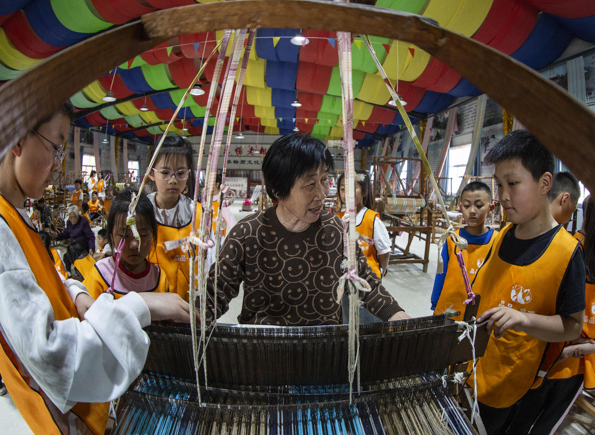 5月1日，在山西省永濟市開張鎮東開張村的惠暢土布文化園，土布製作技師教遊客織布技藝。來源：人民圖片網