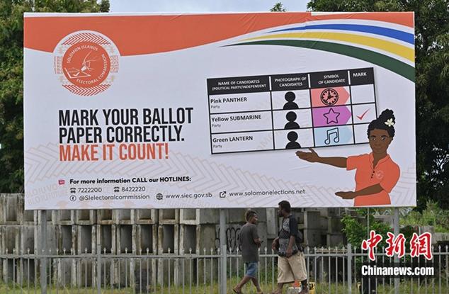 資料圖：當地時間2024年4月16日，所羅門群島首都霍尼亞拉，人們走過展示如何投票的廣告牌。圖/視覺中國