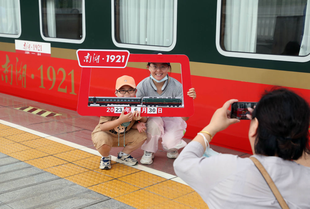   2023年6月30日，旅客在上海至嘉興的Y701次「南湖·1921」紅色旅遊列車旁拍照打卡。新華社記者 劉穎 攝