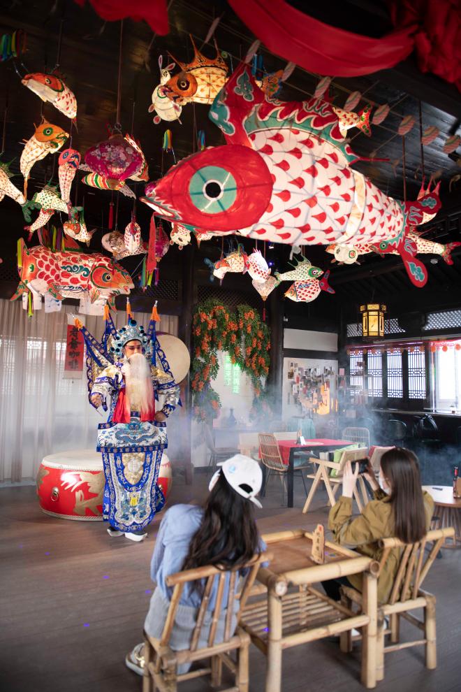   2024年5月19日，遊客在歙縣徽州古城一家魚燈主題咖啡館內欣賞徽劇表演。新華社記者 傅天 攝