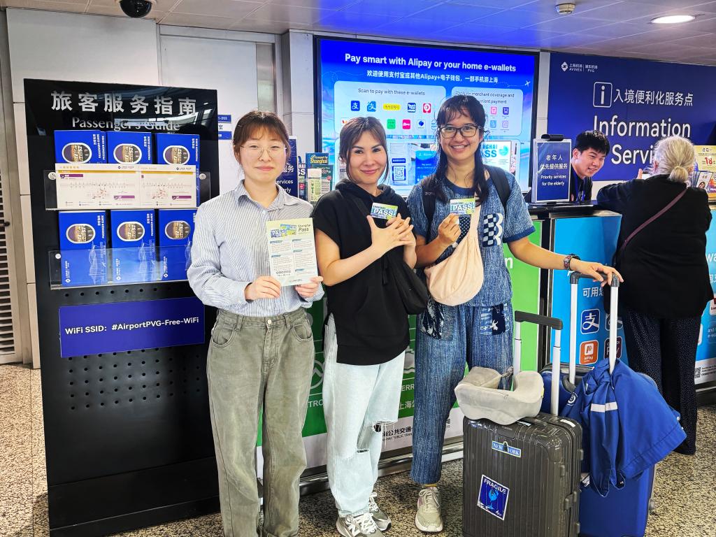 5月24日,泰国游客(中、右)手持“Shanghai Pass”与工作人员合影。新华社发