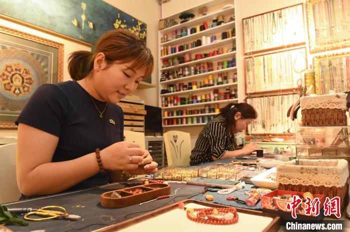 6月12日,在山東煙台一家飾品店,編織師傅忙著編織腕飾。曲正揚 攝