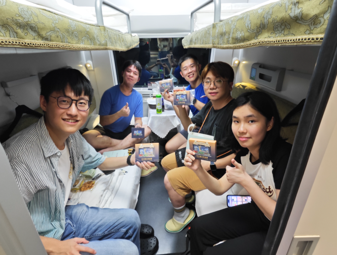 6月15日,乘客在香港西九龙至上海虹桥D908次高铁动卧列车上展示收到的首班车纪念品。新华社 图
