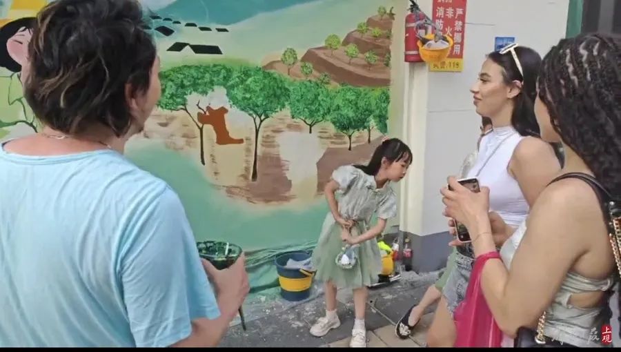 福州路（靠近河南路）旧改地块前，两位外国友人对墙绘产生浓厚兴趣。黄浦区提供