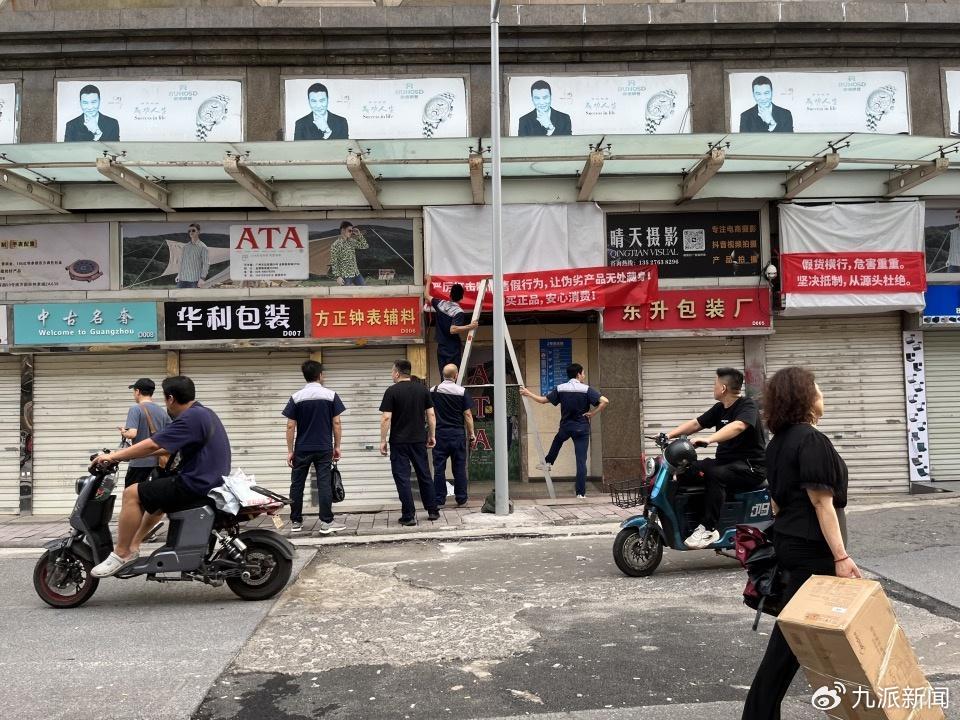 南方国际钟表城街边商铺,商场管理人员装订横幅。 杜逢/摄