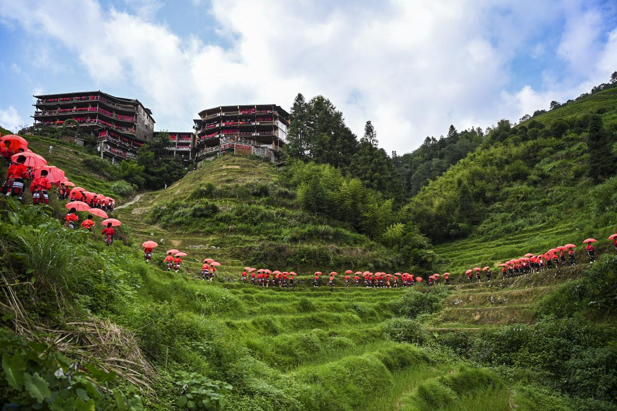 7月11日,在大寨村,當地群眾身著民族服裝走在梯田里。(新華社記者曹禕銘攝)