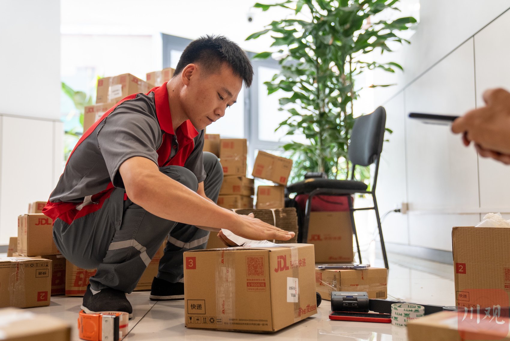 中药房外共有4名快递员进行打包工作,每位快递员身后都隆起了一座“包裹小山”