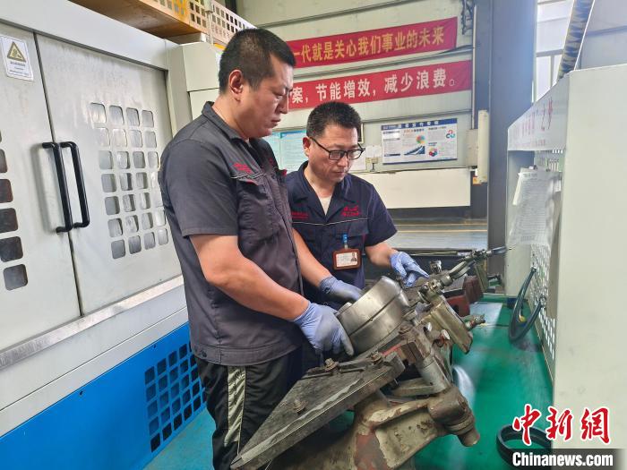 8月14日,李其雙(右一)正在給工人講解軸承機床的產品檢測規範。張靜雯 攝