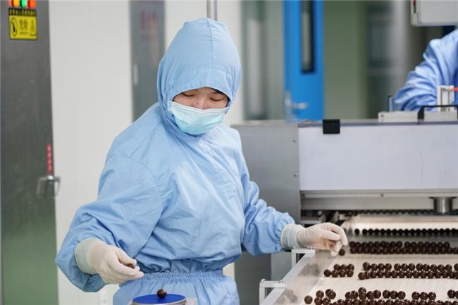 图为同仁堂科技蜜丸车间正在对药丸进行重量差异检查