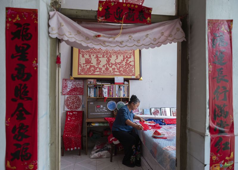 一张张大大小小的红色剪纸作品布满了房间,书架上的家和万事兴剪纸格外醒目。新京报记者 郭延冰 摄