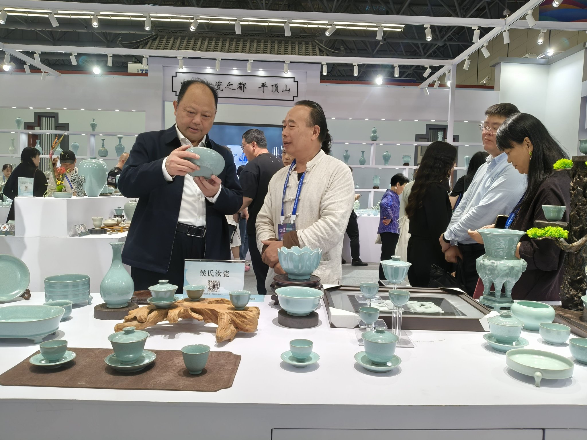 图为宝丰县委书记王代强(左)在景德镇瓷博会“中国汝瓷之都·平顶山”陶瓷馆欣赏汝瓷作品
