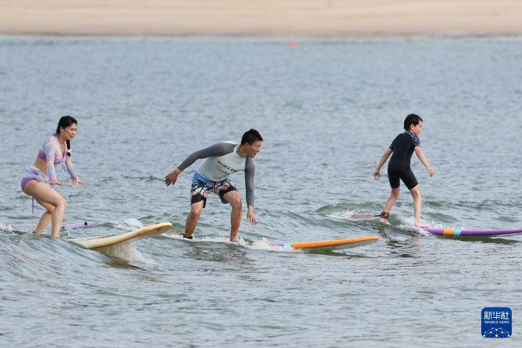 5月21日，遊客在位於三亞海棠灣南端的後海村皇后灣海域衝浪。新華社記者 張麗芸 攝