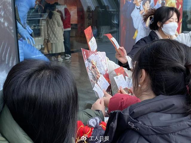 大年初一,上海一家影院外,影迷晒票根与海报合照。图源:澎湃新闻