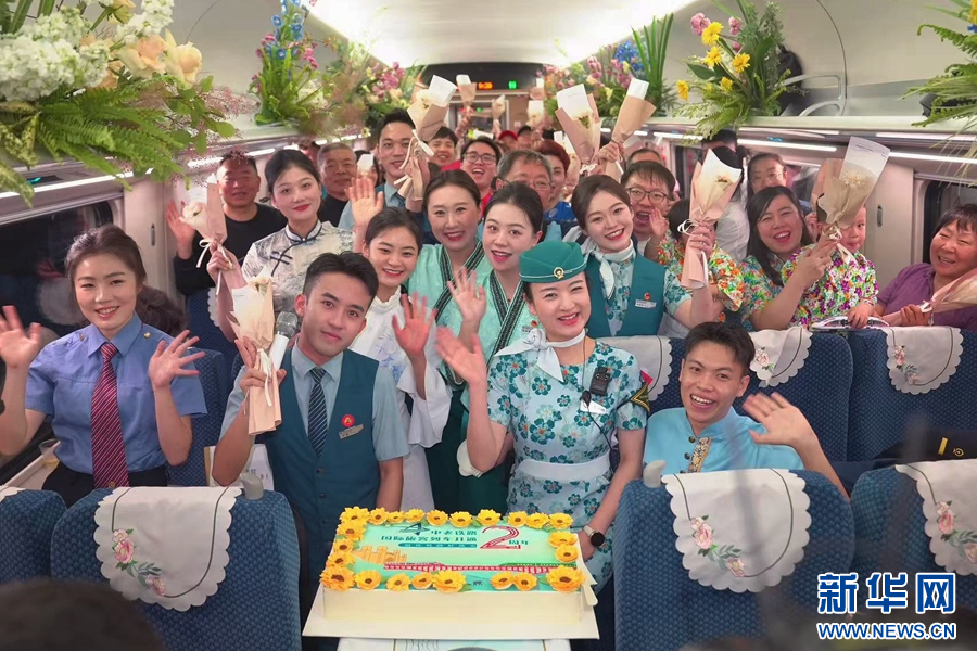 4月12日,D87次國際旅客列車上,工作人員與旅客歡慶中老鐵路國際旅客列車開行兩週年。新華網發(周濤 攝)