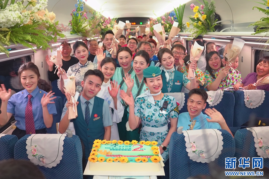 4月12日,D87次國際旅客列車上,工作人員與旅客歡慶中老鐵路國際旅客列車開行兩週年。新華網發(周濤 攝)