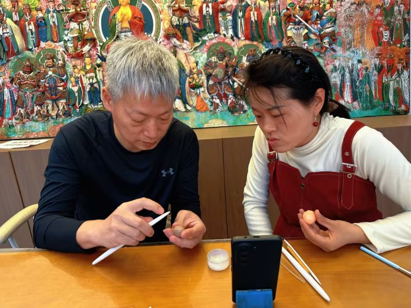 大海面塑店舖內,盧佩宏(左)正在教學徒勾勒人物輪廓。人民網記者 麻潞攝
