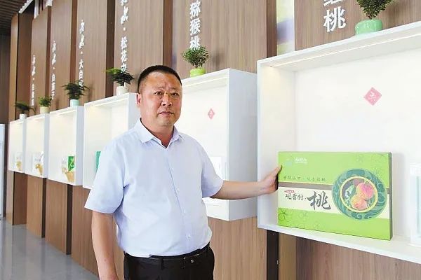 图为全国人大代表熊永俊介绍观音村特产胭脂红桃产业发展情况。