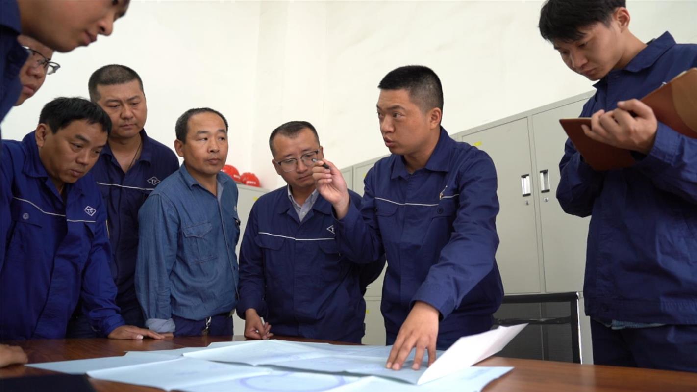 褚建華與同事在探討技改方案。(資料圖)