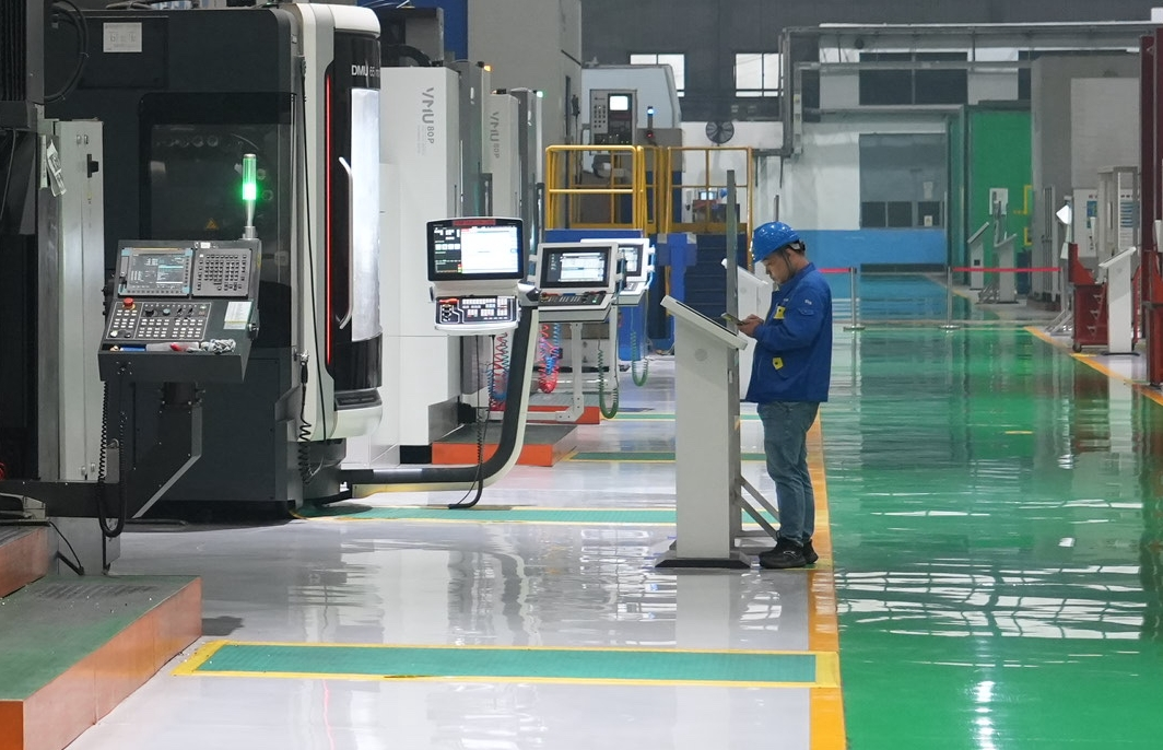 沈鼓集團轉子車間里,技術工人在屏幕上佈置任務,身邊的數控機床開始精雕細刻。人民網記者 周頌雪攝