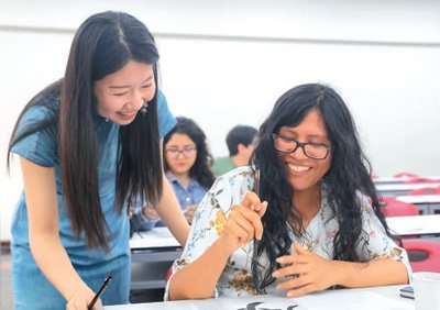 圖為在秘魯利馬,秘魯天主教大學孔子學院中文教師梁卿(左)輔導秘魯學生寫書法。