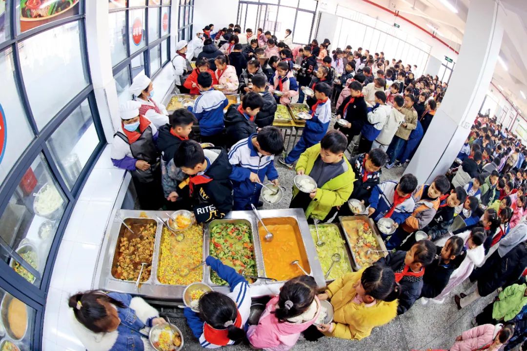 2025年2月17日,廣西柳州融安縣浮石鎮中心小學食堂,學生們在排隊打飯菜。