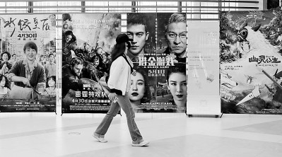     在上海某家电影院，观众经过“五一档”电影海报。光明图片/视觉中国
