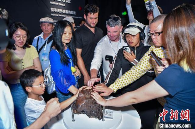6月10日,游客在文昌极星陨石博物馆触摸感知陨石标本。中新网记者 骆云飞 摄