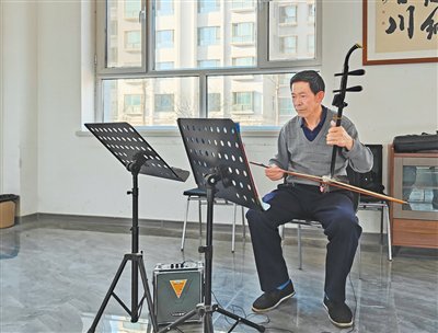 横梁乡绿洲“一老一幼”关爱服务中心里，苟正升在拉二胡。人民日报记者 宋朝军摄