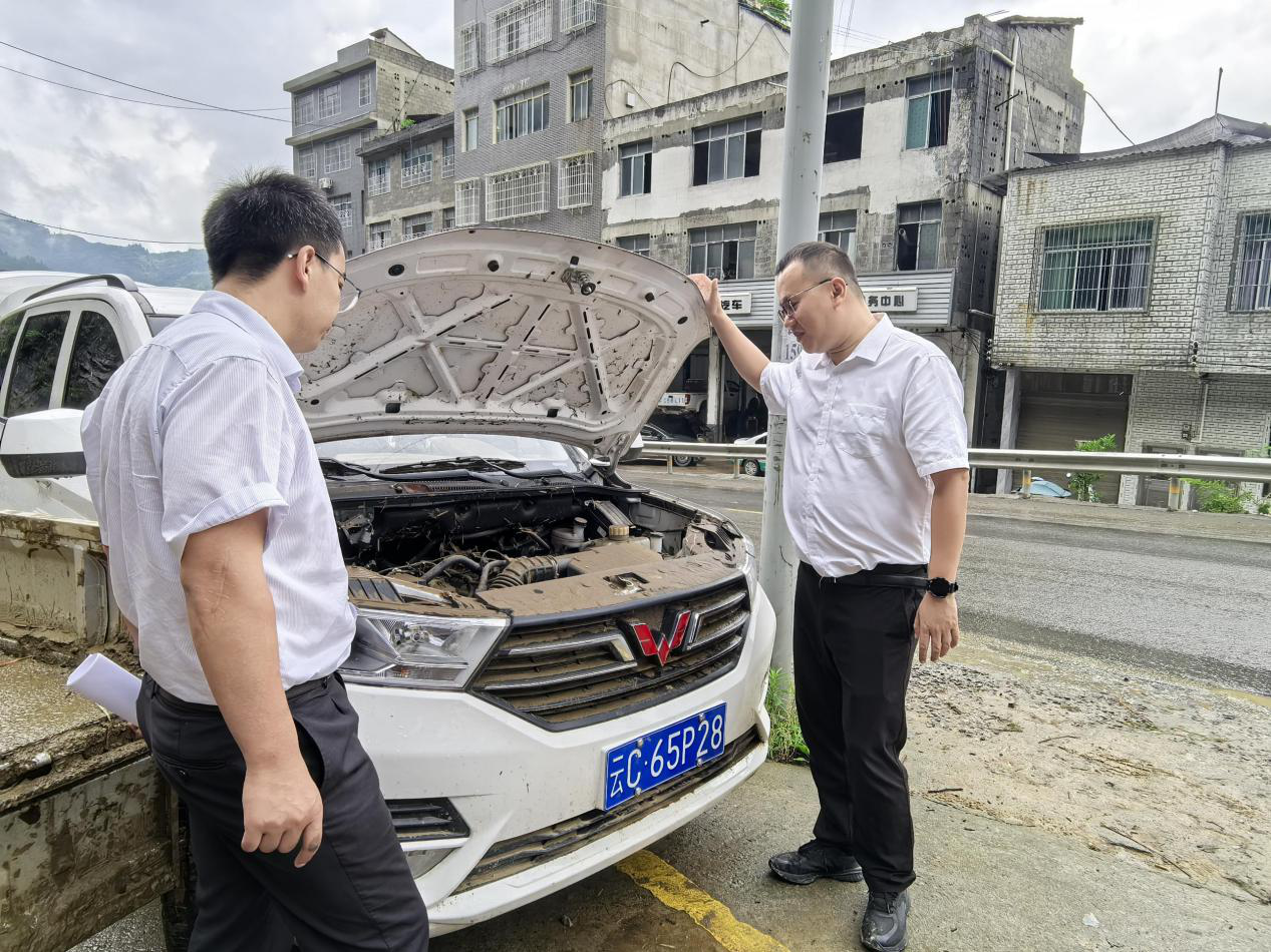 7月10日,中国人寿财险云南省分公司理赔服务部负责人陈冬(右)到维修网点协商定损方案。(李雄武摄)