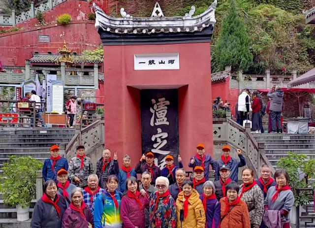 (10月22日,来自广西贺州的部分离退休人员佩戴“红领巾”在泸定桥西桥头“河山统一”标牌前合影。王建明摄)