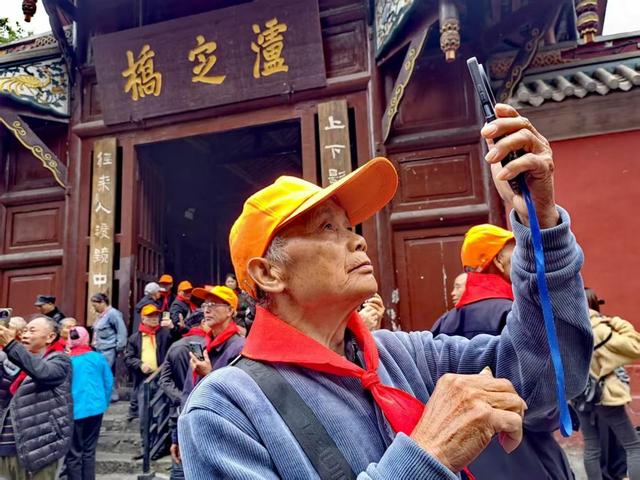 (10月22日,来自广西贺州的何大爷在泸定桥头用手机视频方式给老家亲人分享参观心情 王建明摄)