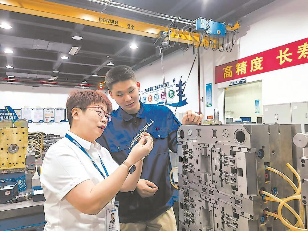在宏发电声车间,企业导师(左)正在指导“精匠班”学生。本报记者 赵文娟 摄