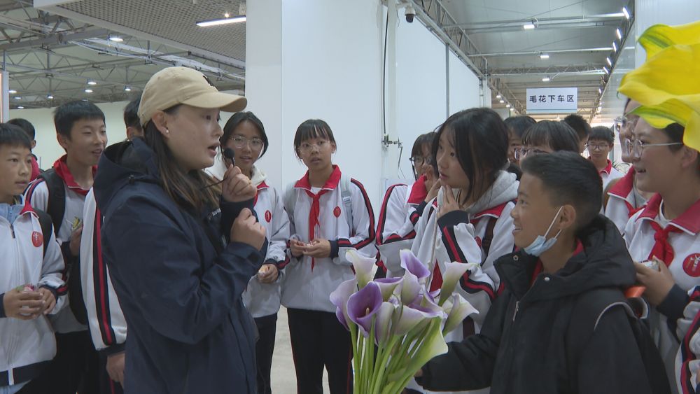 同学们参观鲜花展示区并认真聆听讲解。（丽江融媒记者 和继鹏 摄）