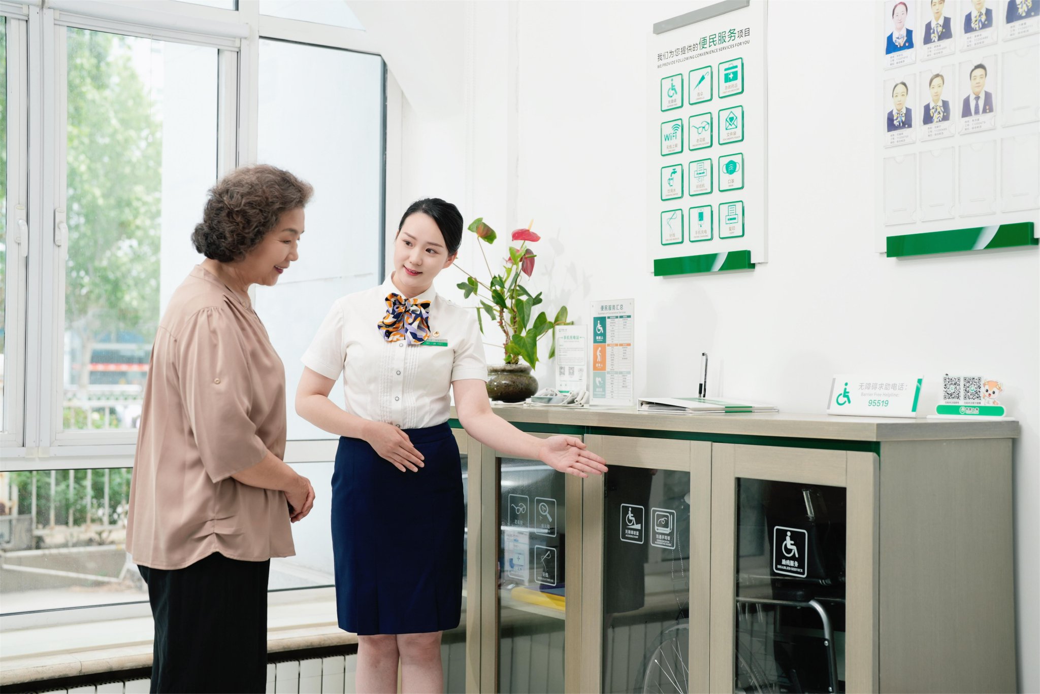 图：柜面服务人员为老年客户介绍适老化服务设施。