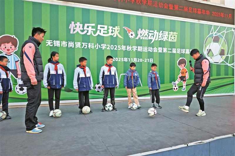 20日，夏锡成（左一）和吴磊（右一）在校园指导孩子踢球。 