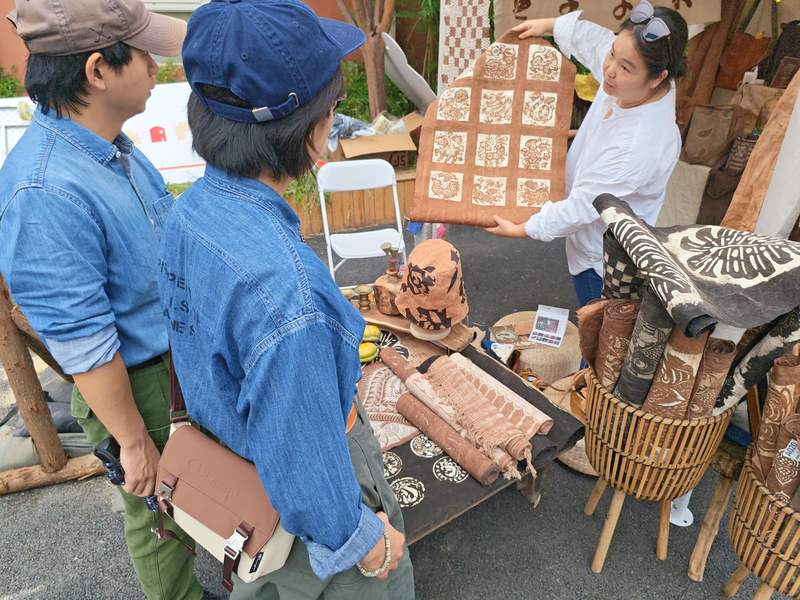 上新街市集一位非遗植物染布摊位引来游客驻足观看体验草木扎染。