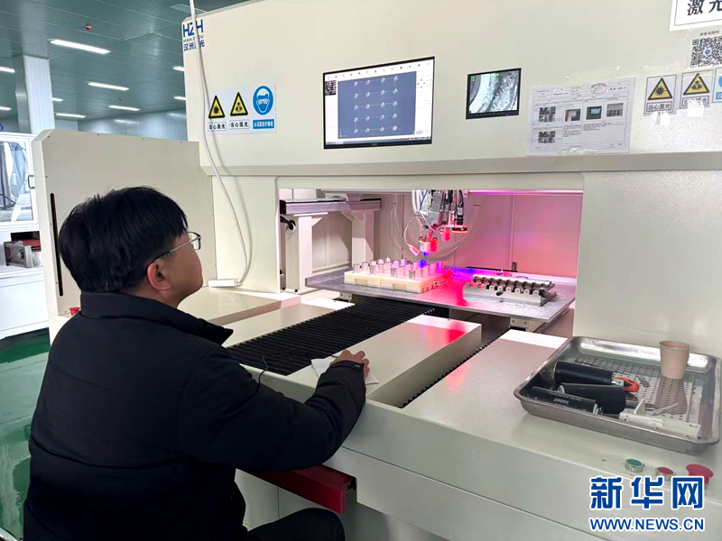 圖為工作人員在激光設備前銲接電容器的正極引出爪和負極連接片。新華網（劉欣瑜 攝）