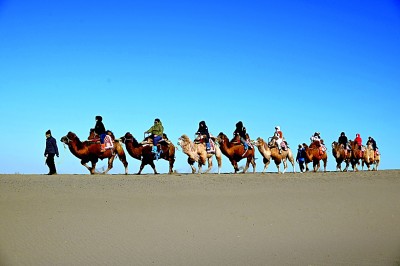 　　游客在甘肃省敦煌市鸣沙山月牙泉景区游览。新华社发