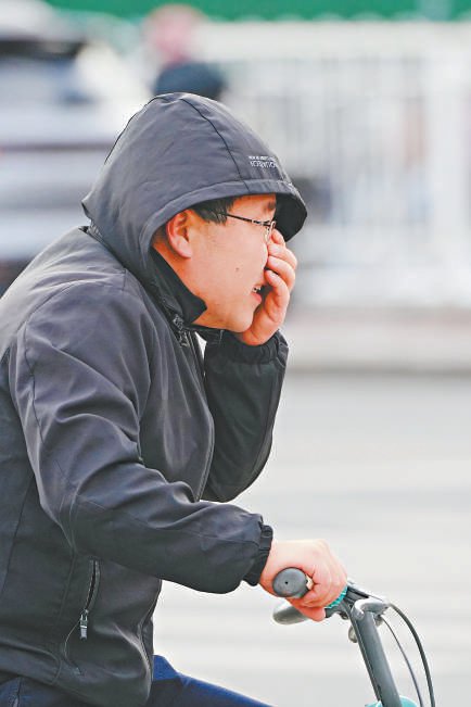昨天，海淀区五道口，一位市民骑着自行车在风中出行。 本报记者 王海欣摄