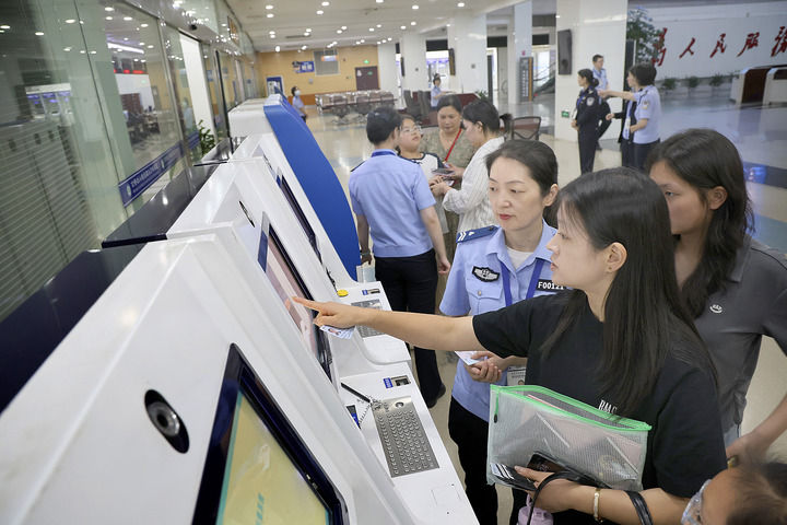 2025年6月25日，工作人員在江蘇南通市政務中心出入境辦證大廳指導市民使用自助填表系統。新華社發（許叢軍攝）