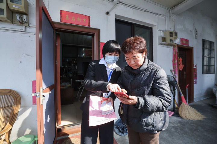 2025年12月18日，浙江省諸暨市東白湖鎮事業綜合服務中心的黨員誌願者（左）上門「一對一」指導村民使用「浙里辦」數字化平台辦理業務。新華社記者 徐昱 攝