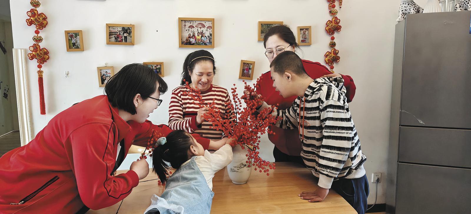 曾国存（右三）和福利院的老师一起陪孩子们制作春节的装饰品。本报记者 丁玉梅 摄