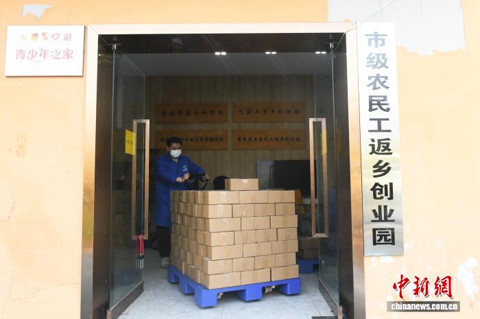 圖為工人將打包好的臘味年貨送往快遞站。中新社記者 周毅 攝