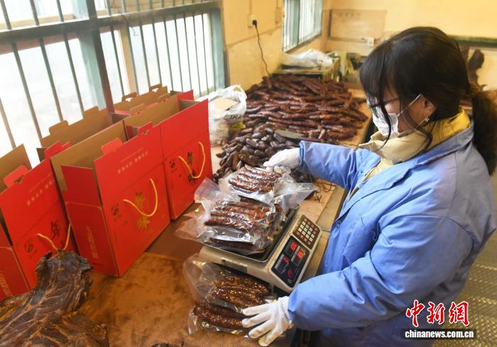 圖為工人將包裝好的臘味製品稱重裝箱。中新社記者 周毅 攝
