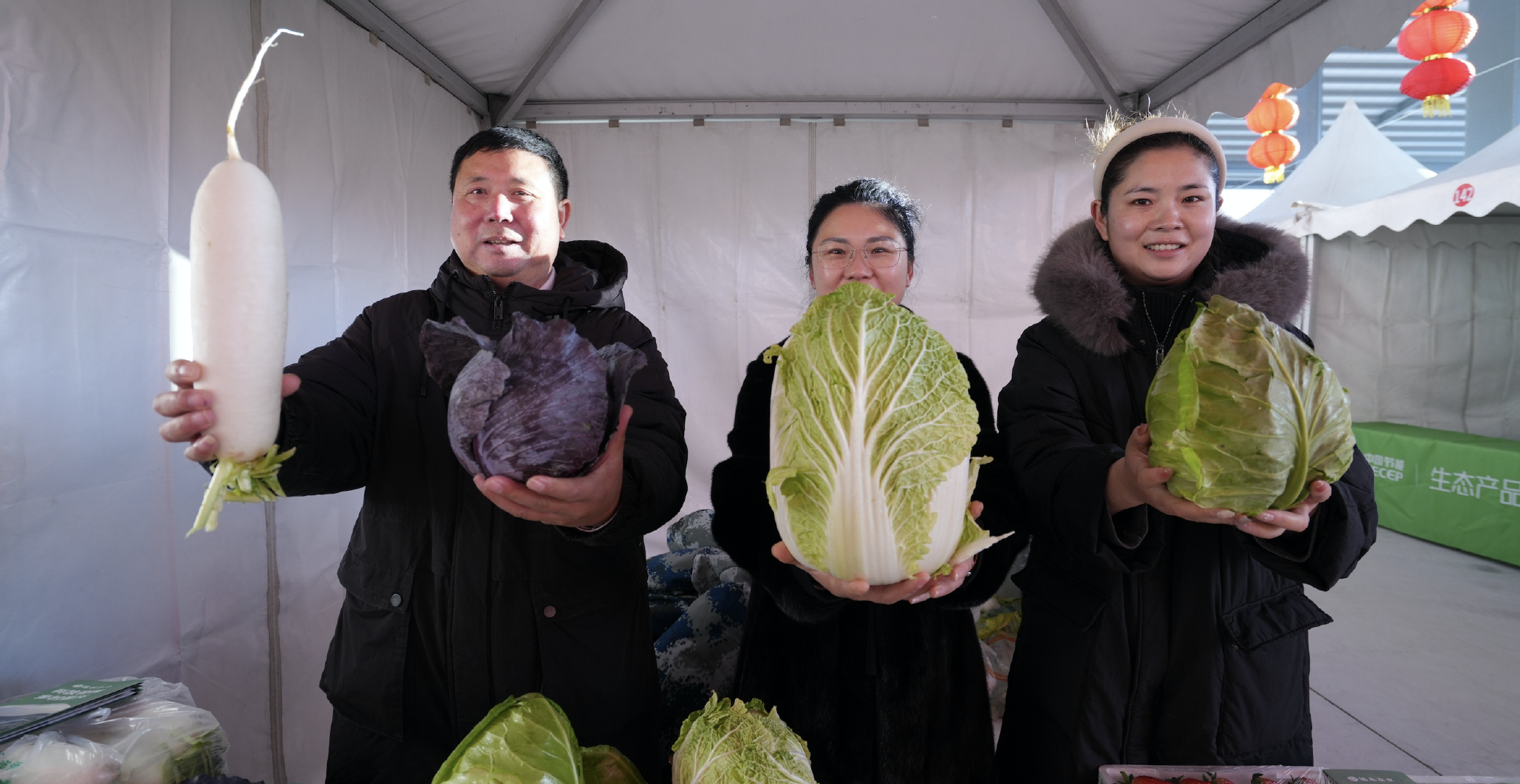 图为新发地年货节现场，商户向记者展示农产品。​