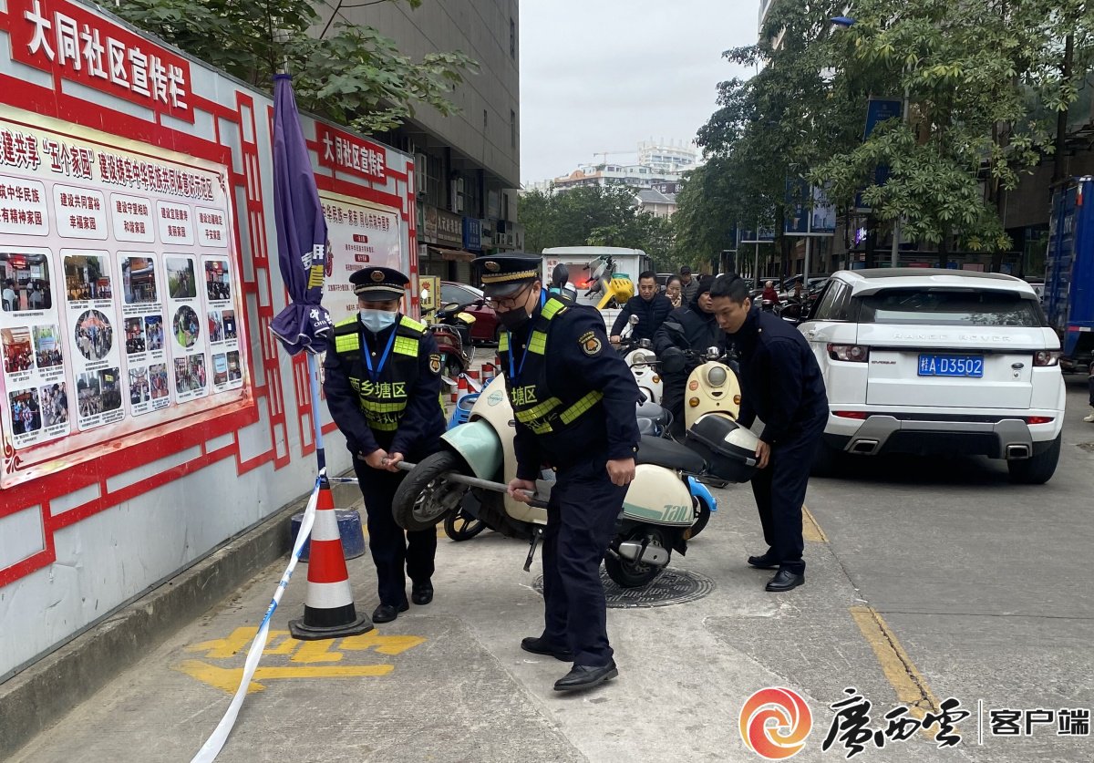 南寧市西鄉塘區城管執法隊員與社區、物業工作人員整治電動車亂停放現象。覃莉玲 攝