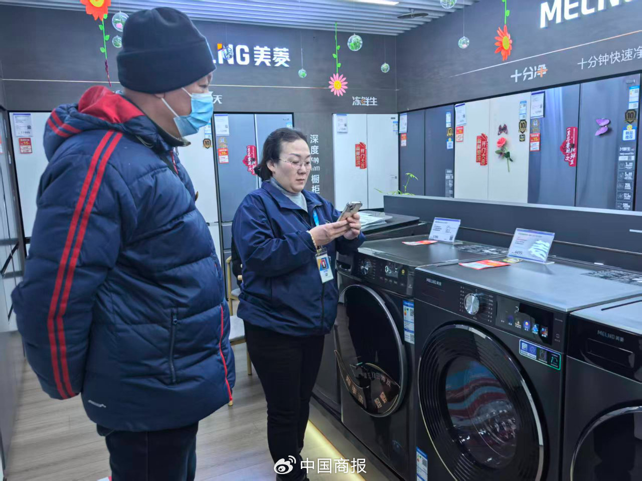 苏宁易购门店的销售人员正在向顾客详细介绍各种功能。