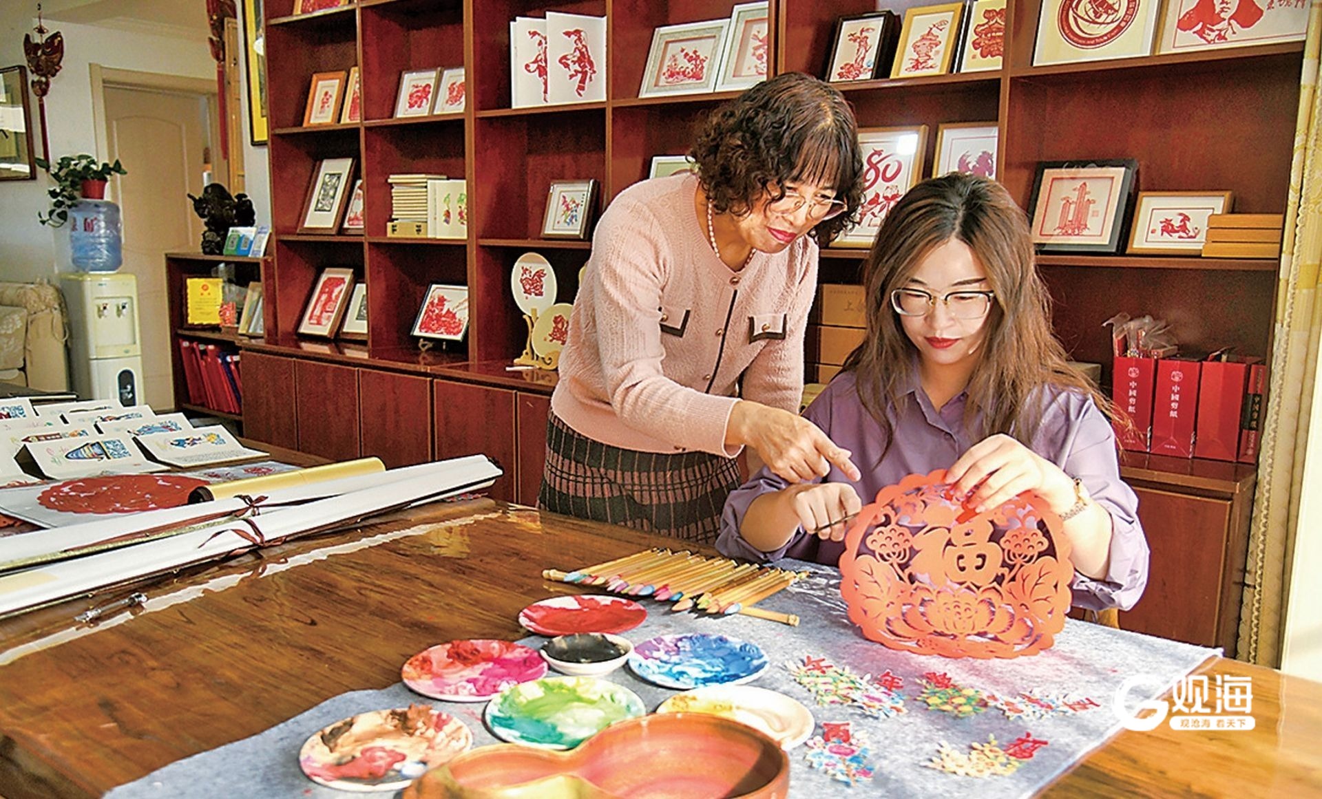 “90后”传承人高瑜桓（右）和母亲李秀君一起探讨剪纸艺术。王雷 摄