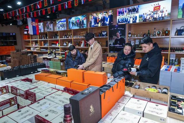 1月30日，在浙江义乌中国进口商品城一家店铺内，店员给顾客推荐塞尔维亚葡萄酒。新华社记者 徐昱 摄